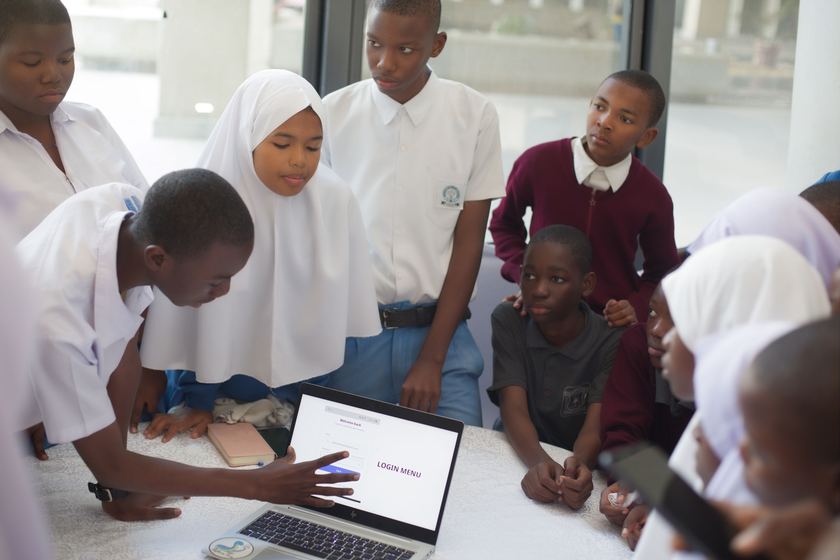 Student pointing at a software login screen while classmates watch