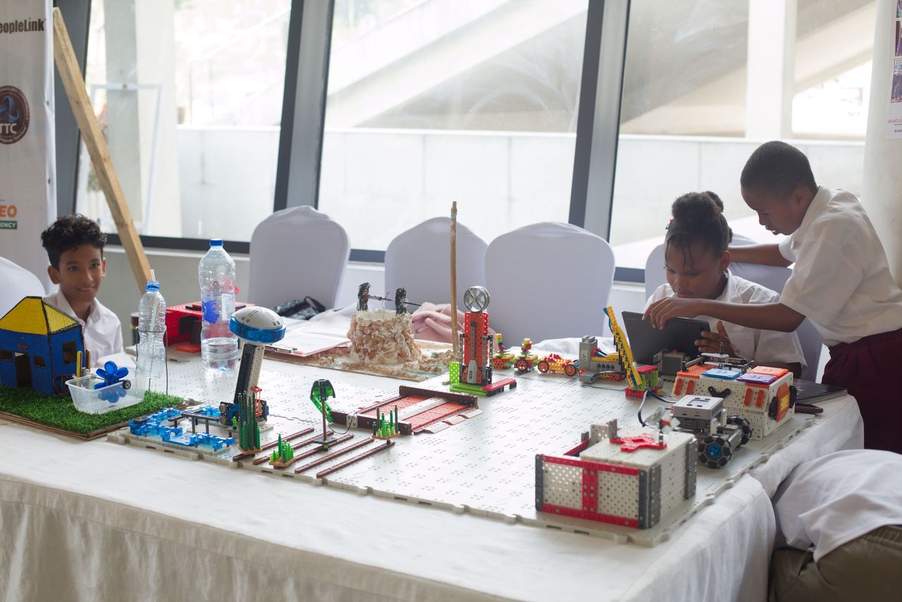 Students with robotics kits, energy models and a tablet at their exhibition table